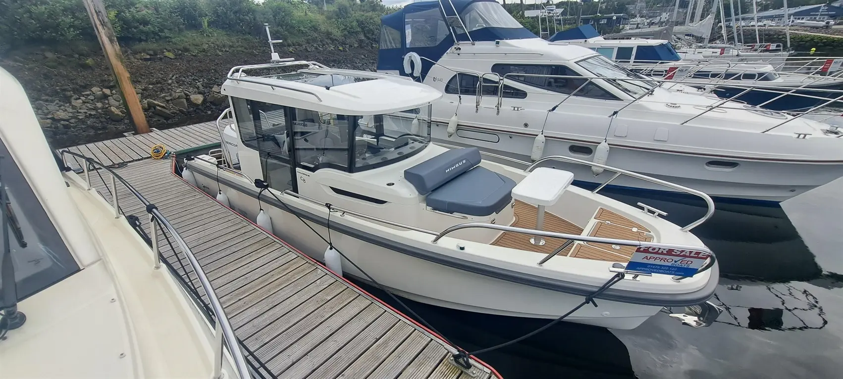 Nimbus boat for sale at the marina, featuring a spacious cockpit and modern design, alongside other moored vessels.